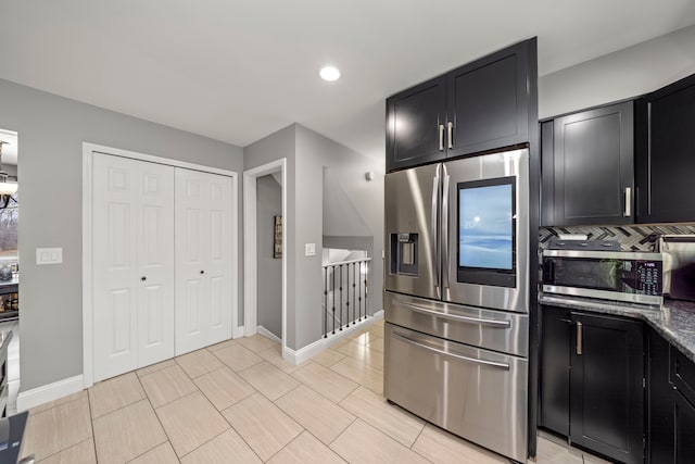 kitchen featuring appliances with stainless steel finishes, dark stone counters, and dark cabinets