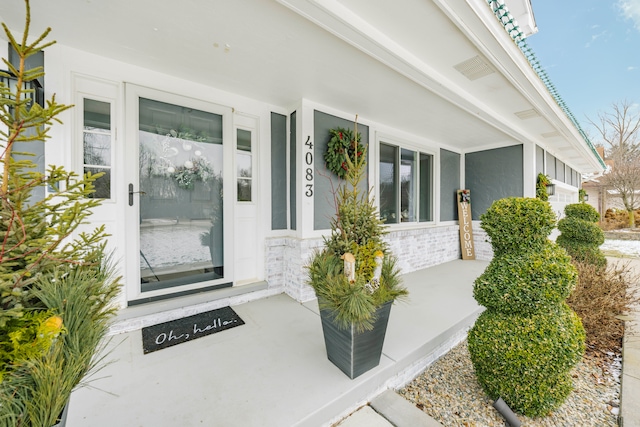 view of exterior entry with a porch and stucco siding