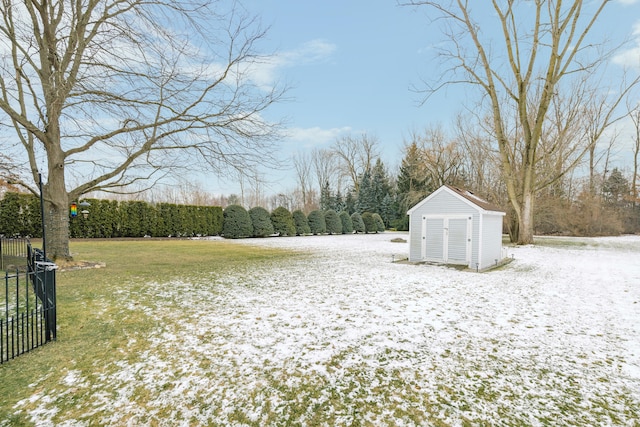 yard layered in snow featuring an outbuilding, fence, and a shed