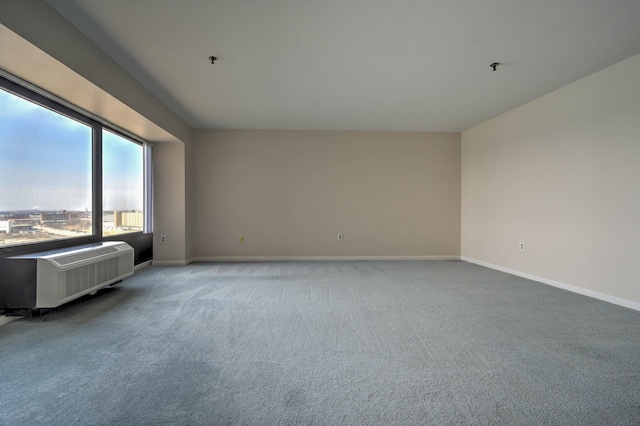 spare room featuring a wall unit AC, light carpet, and baseboards