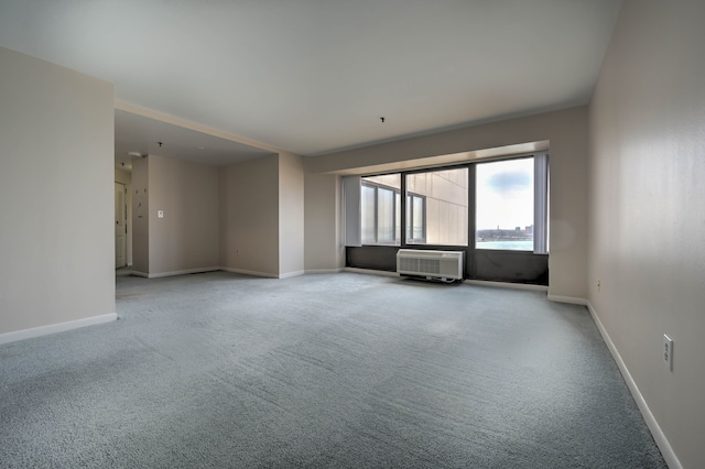 empty room featuring a wall mounted air conditioner, carpet flooring, and baseboards