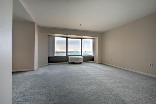 carpeted empty room featuring a wall unit AC and baseboards