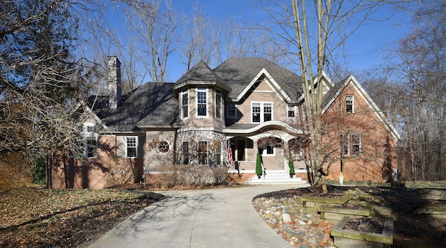 view of front of property with brick siding, driveway, and a chimney