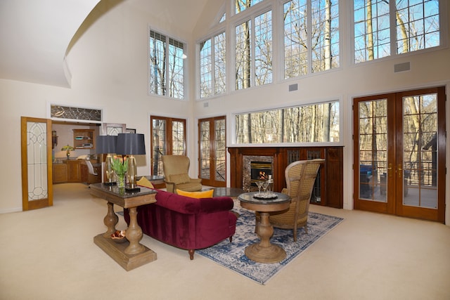 living area featuring a high end fireplace, visible vents, french doors, and carpet floors