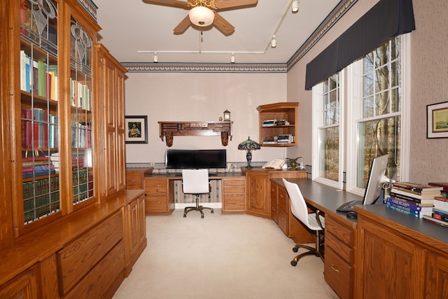 home office with a ceiling fan, light colored carpet, track lighting, and built in study area