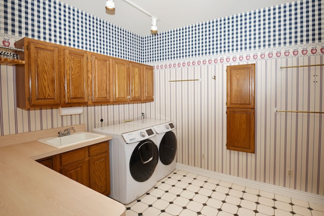 laundry room with a sink, cabinet space, wallpapered walls, light floors, and washing machine and clothes dryer