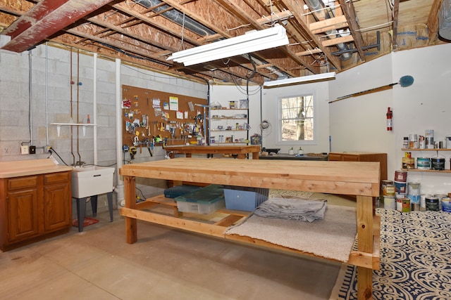 basement with a workshop area, concrete block wall, and a sink