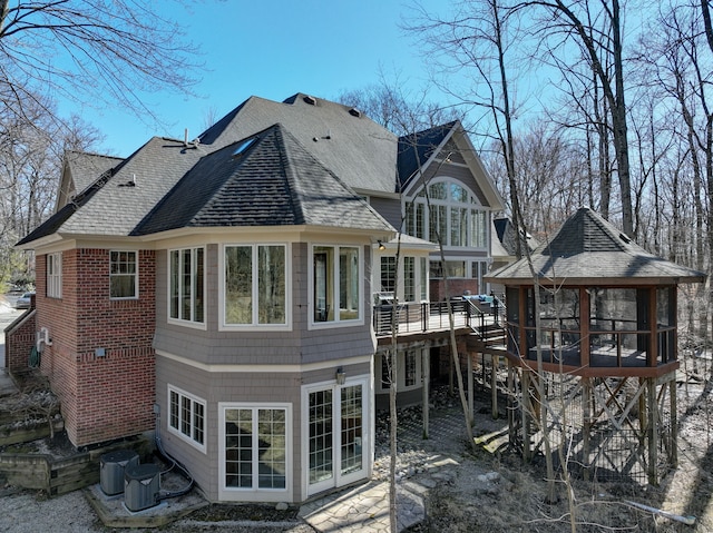 rear view of house with a gazebo, central AC, roof with shingles, and a deck