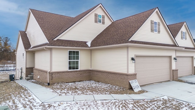 view of front of property featuring concrete driveway, brick siding, roof with shingles, and an attached garage