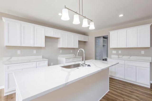 kitchen featuring an island with sink, white cabinets, a sink, and wood finished floors