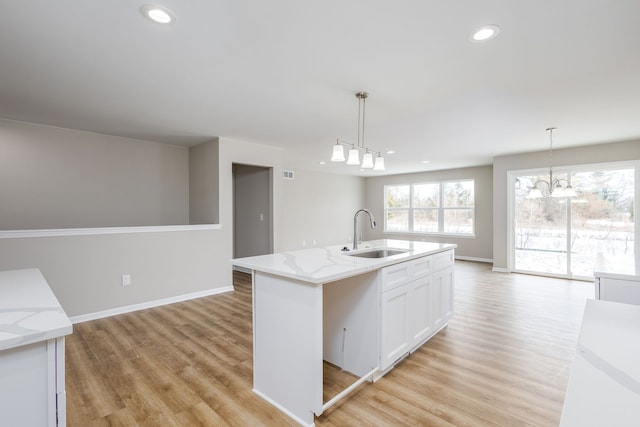 kitchen with light wood finished floors, a sink, white cabinetry, and recessed lighting