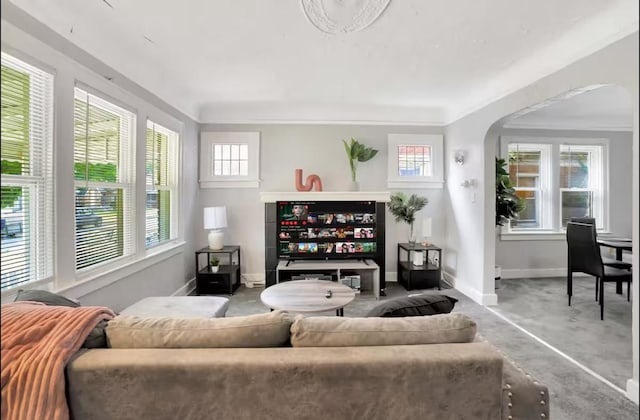 living room with arched walkways, carpet flooring, and baseboards