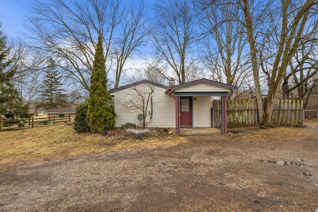 view of front of property with dirt driveway, a chimney, and fence