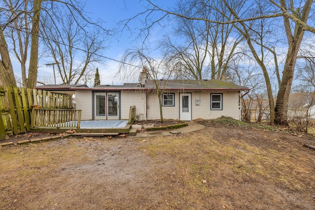 ranch-style house with fence, a chimney, and a wooden deck