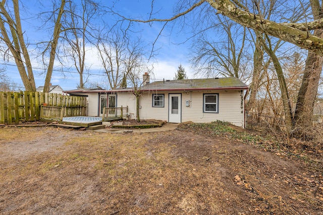 view of front of property featuring a deck, fence, and a chimney