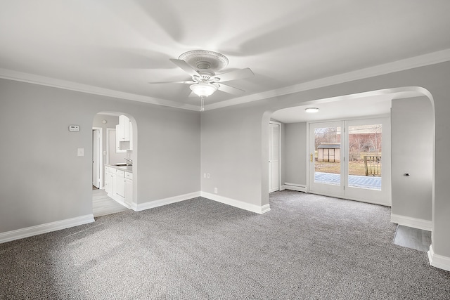 spare room with baseboards, arched walkways, carpet flooring, a baseboard heating unit, and a sink