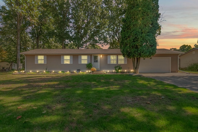 single story home with an attached garage, driveway, and a lawn