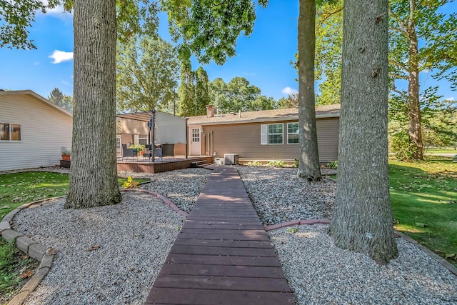 rear view of property with a chimney, a lawn, a deck, and central AC