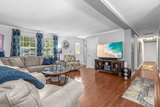 living room featuring ornamental molding, wood finished floors, visible vents, and baseboards