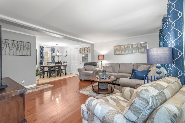 living room with an inviting chandelier, ornamental molding, and wood finished floors