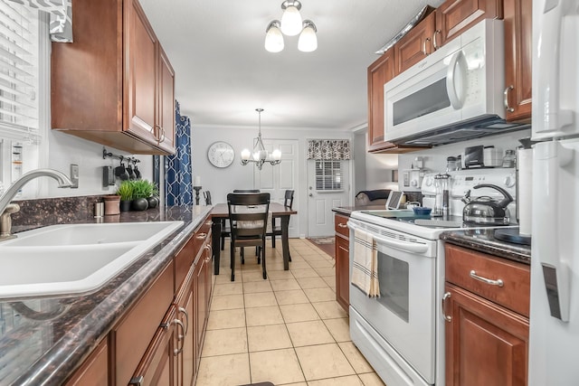 kitchen with light tile patterned floors, a notable chandelier, white appliances, a sink, and dark countertops