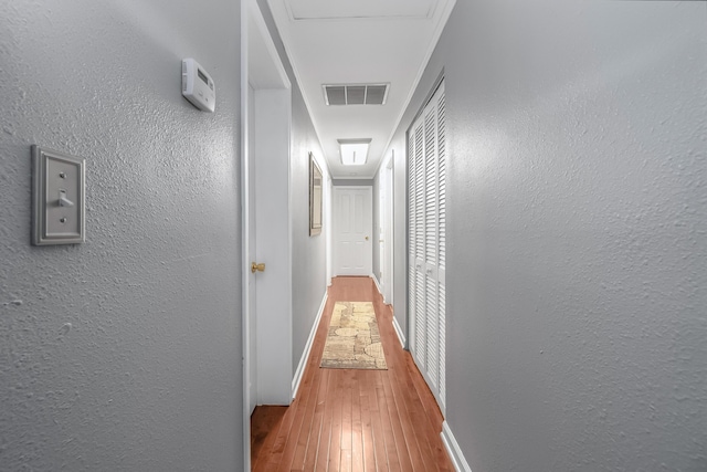 hall featuring a textured wall, hardwood / wood-style flooring, and visible vents