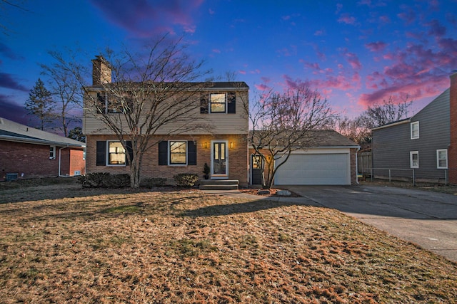 colonial inspired home featuring a garage, brick siding, fence, concrete driveway, and a chimney