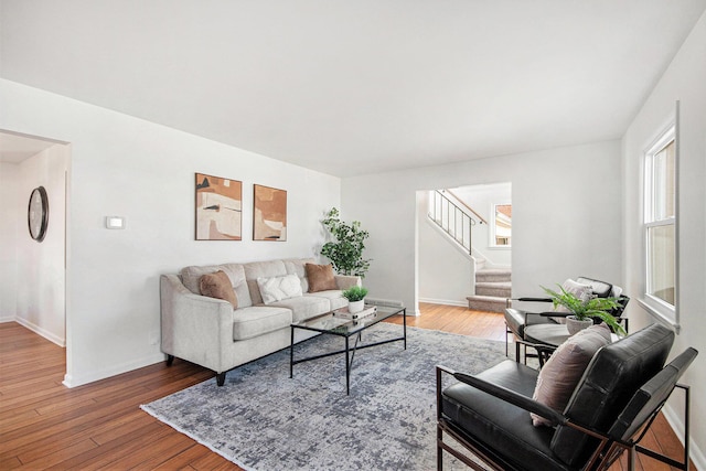 living room featuring stairs, hardwood / wood-style flooring, and baseboards