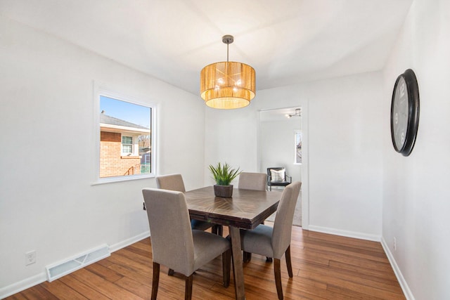 dining room with an inviting chandelier, baseboards, visible vents, and hardwood / wood-style floors