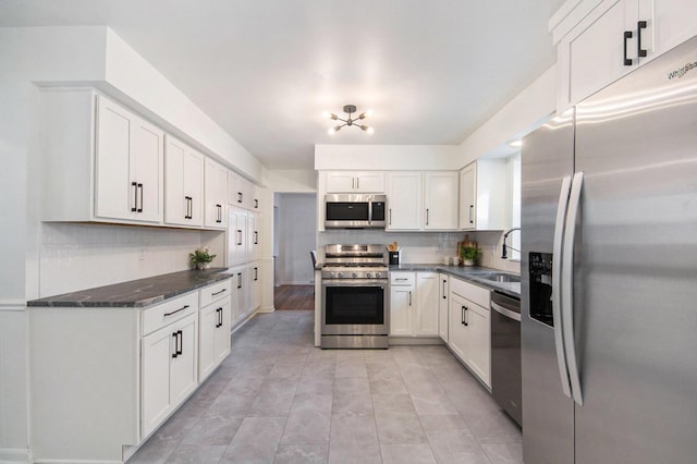 kitchen featuring stainless steel appliances, a sink, white cabinets, and decorative backsplash