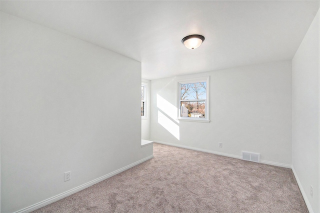 carpeted spare room with visible vents and baseboards