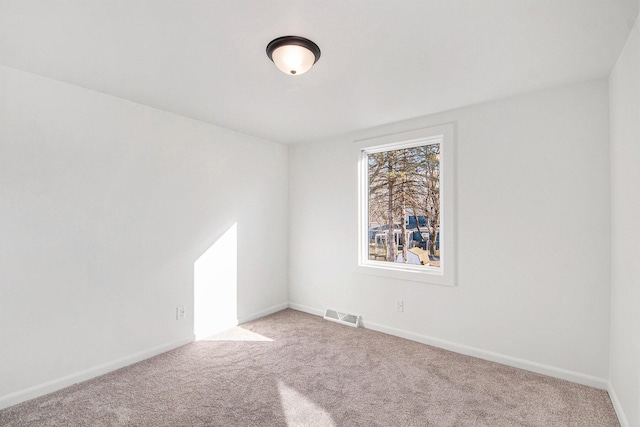 carpeted spare room with visible vents and baseboards