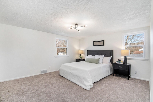 bedroom with light carpet, multiple windows, visible vents, and baseboards