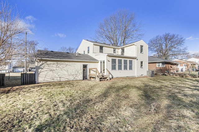 rear view of property featuring cooling unit, fence, and a lawn