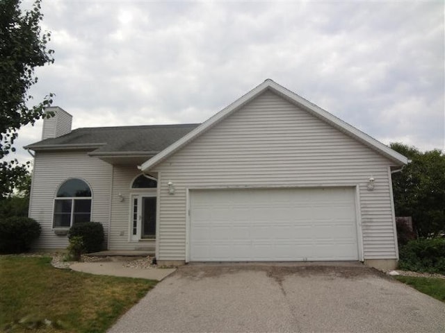 view of front of property featuring a garage, a chimney, and aphalt driveway