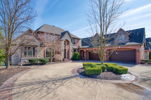 view of front of property featuring brick siding, a garage, stone siding, and curved driveway