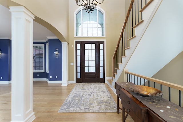 entrance foyer with arched walkways, light wood-type flooring, a towering ceiling, and a chandelier