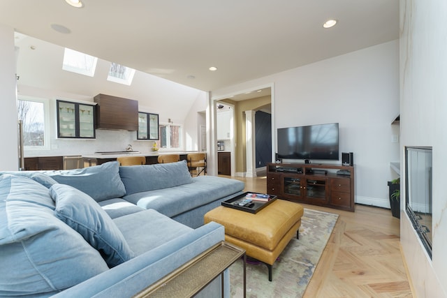 living room featuring recessed lighting, baseboards, and vaulted ceiling with skylight