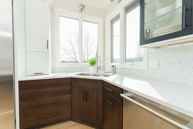 kitchen with dishwasher, light countertops, a wealth of natural light, and a sink