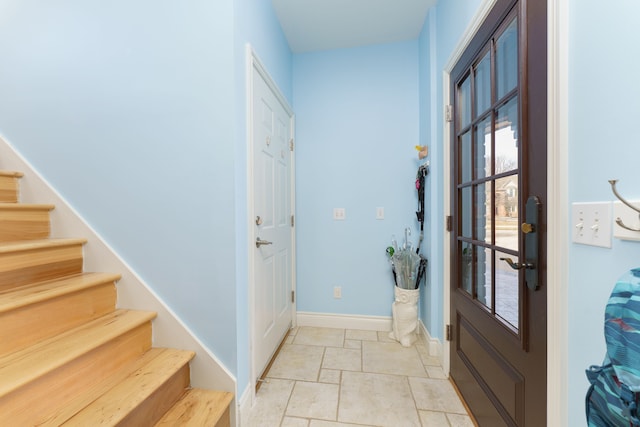 foyer entrance with baseboards and stairs