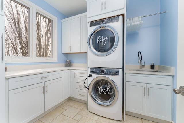 laundry area with a sink, cabinet space, and stacked washer and dryer