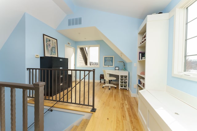 home office featuring visible vents, baseboards, lofted ceiling, and light wood-style floors