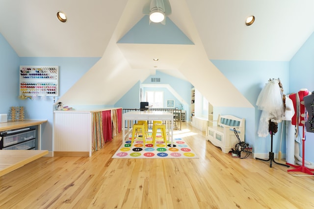 recreation room with lofted ceiling, wood finished floors, visible vents, and ceiling fan