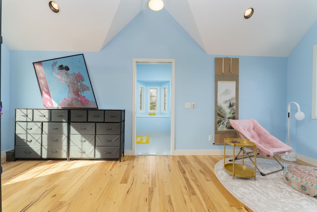 living area featuring vaulted ceiling, wood finished floors, and baseboards