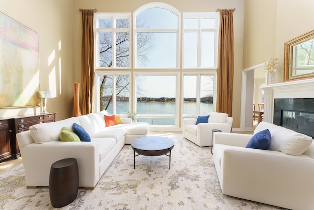 living area with a towering ceiling, a water view, and a high end fireplace