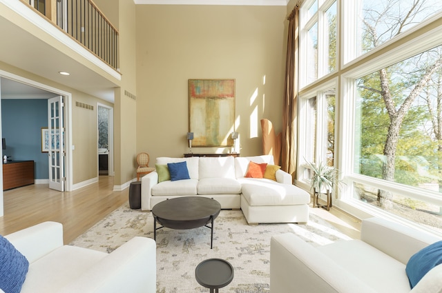 living room with a high ceiling, wood finished floors, visible vents, and baseboards