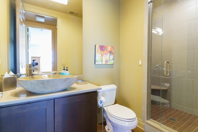 bathroom featuring visible vents, toilet, a stall shower, and vanity