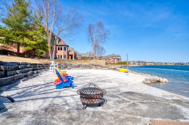 exterior space with a water view, a fire pit, and a beach view