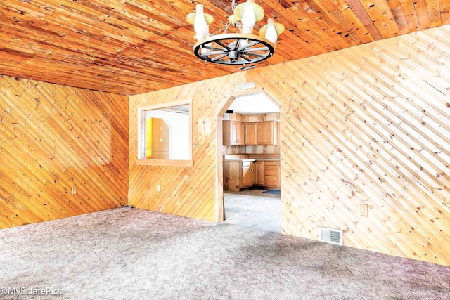 carpeted spare room with wood walls, wooden ceiling, and visible vents