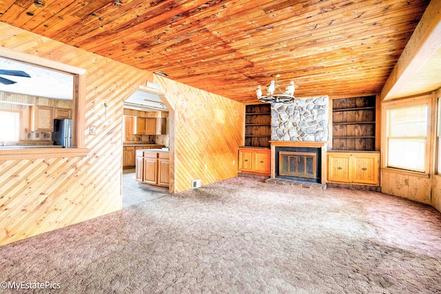 unfurnished living room with wooden ceiling, light carpet, and wooden walls